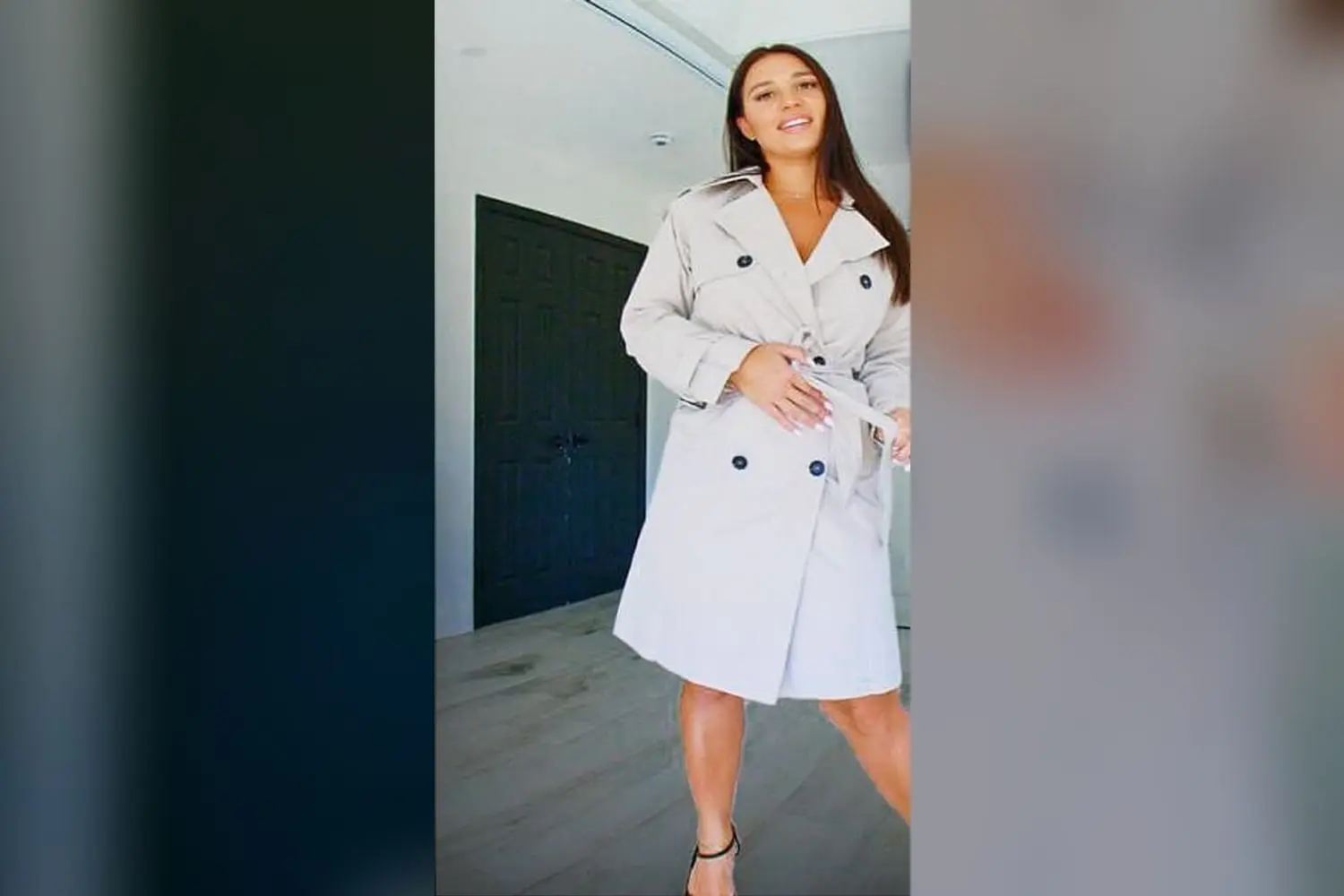 Lexis Star in a beige trench coat and black heels in a bright bedroom, the LustLabz cuckold VR porn scene Real Cuck Experience on VRPorn.com